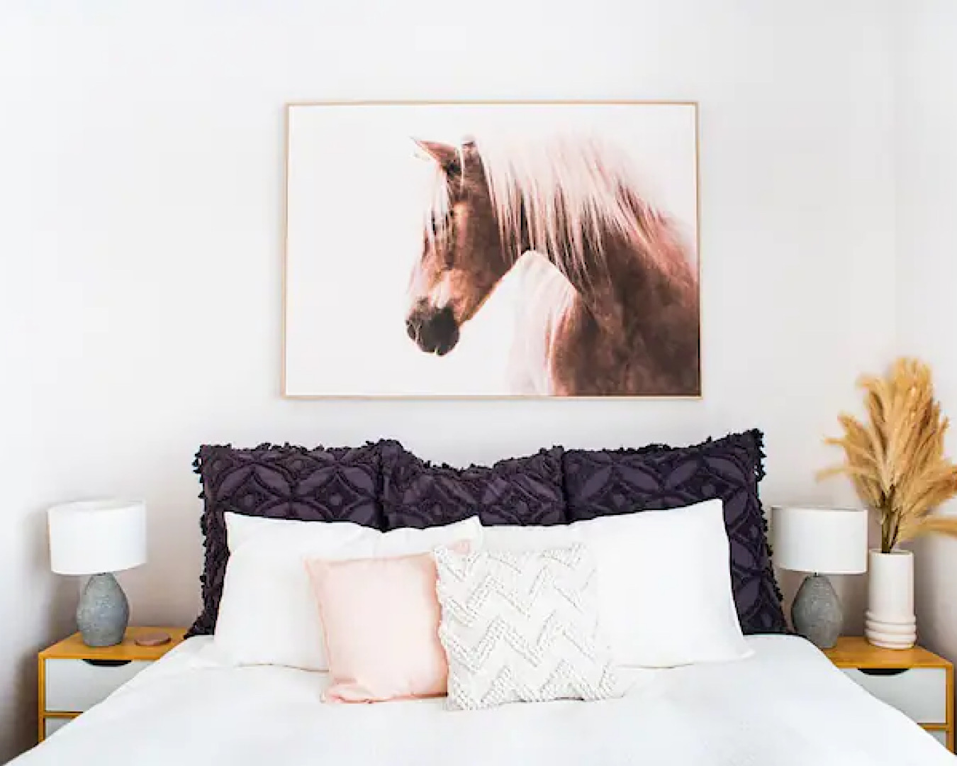 A pretty pink and white bed and a portrait of a horse at The Pool House, one of the best airbnbs near Hamilton. 