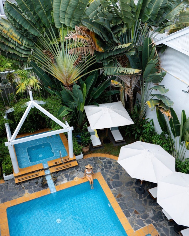 A view of white umbrellas by the pool at The Reef House one of the best hotels in Cairns