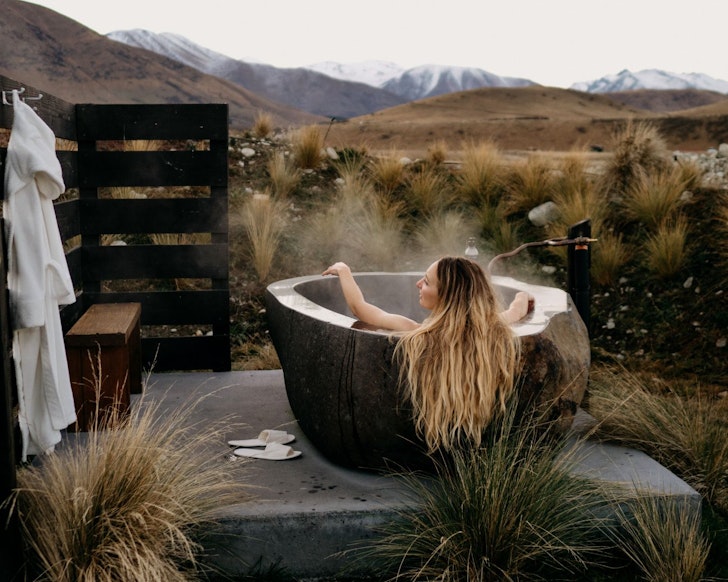 A woman relaxes in the outdoor bath at The Rise Airbnb New Zealand