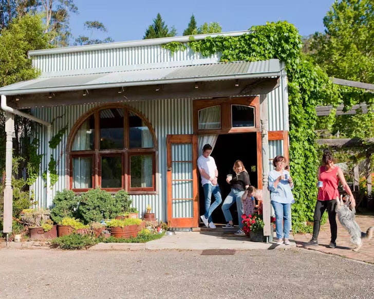 Guests gather outside the corrugated iron frontage of The Shed one of the best pet-friendly stays near Sydney