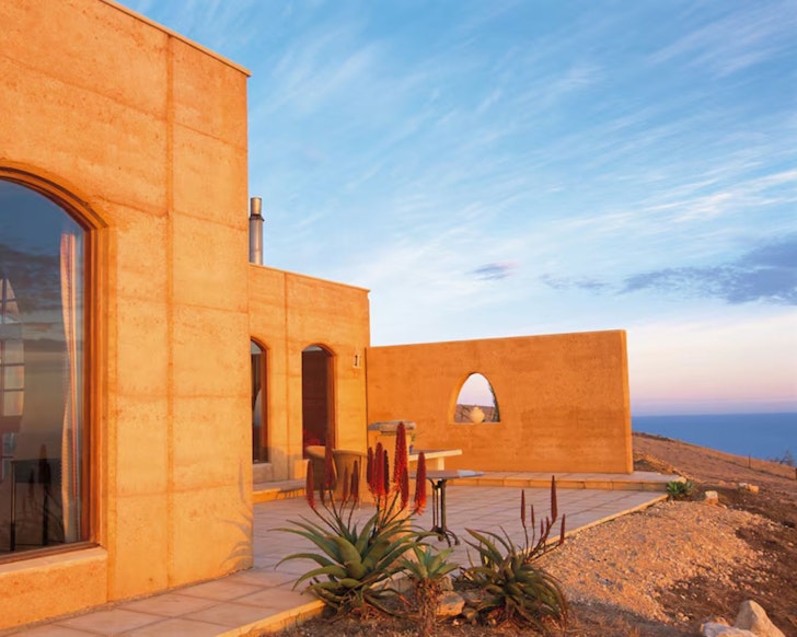 An exterior view of the rammed earth Sky House with a view over the water. One of the best Airbnbs in South Australia