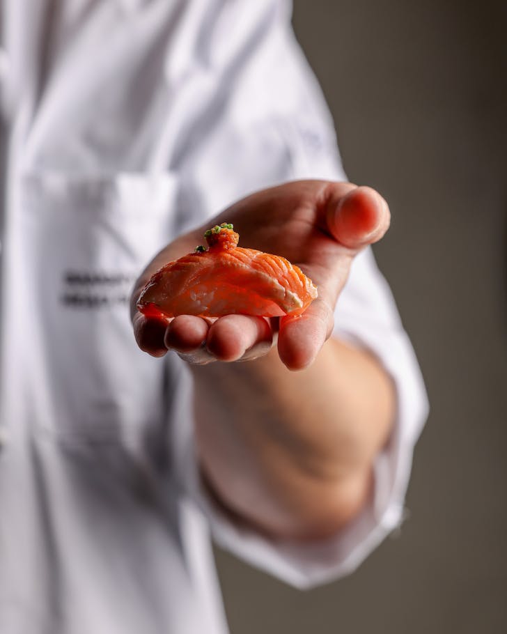 a chef presents a piece of salmon nigiri at sydney omakase sokyo