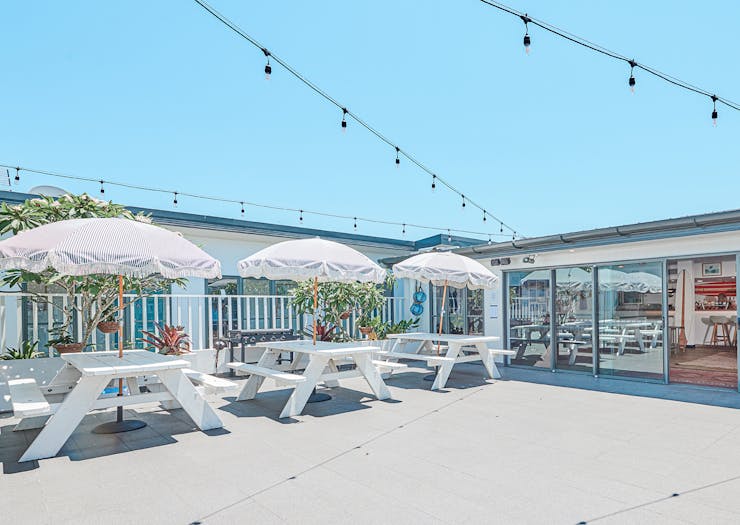 The rooftop bar, kitted out with picnic tables and beach umbrellas, at Byron Bay's The Surf House.