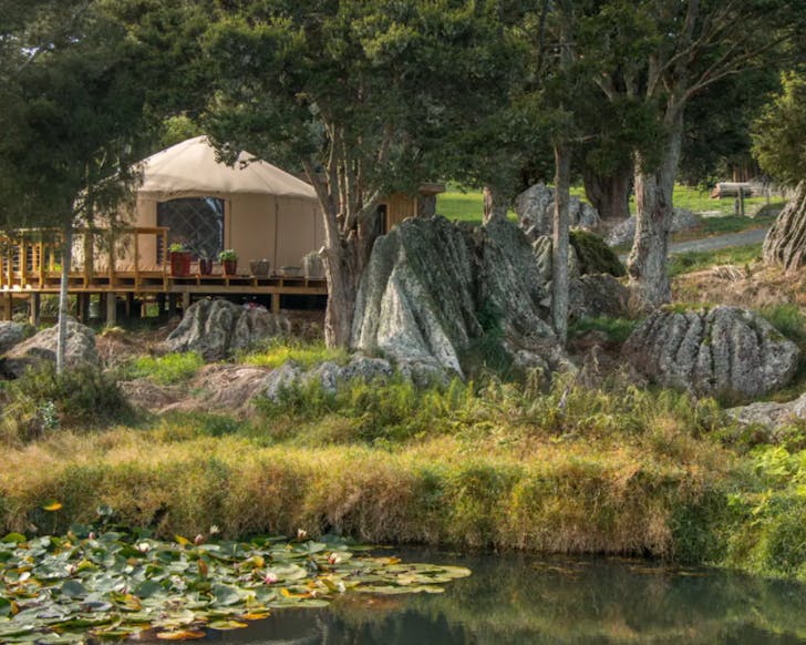 A yurt with a deck looking out over a pond 