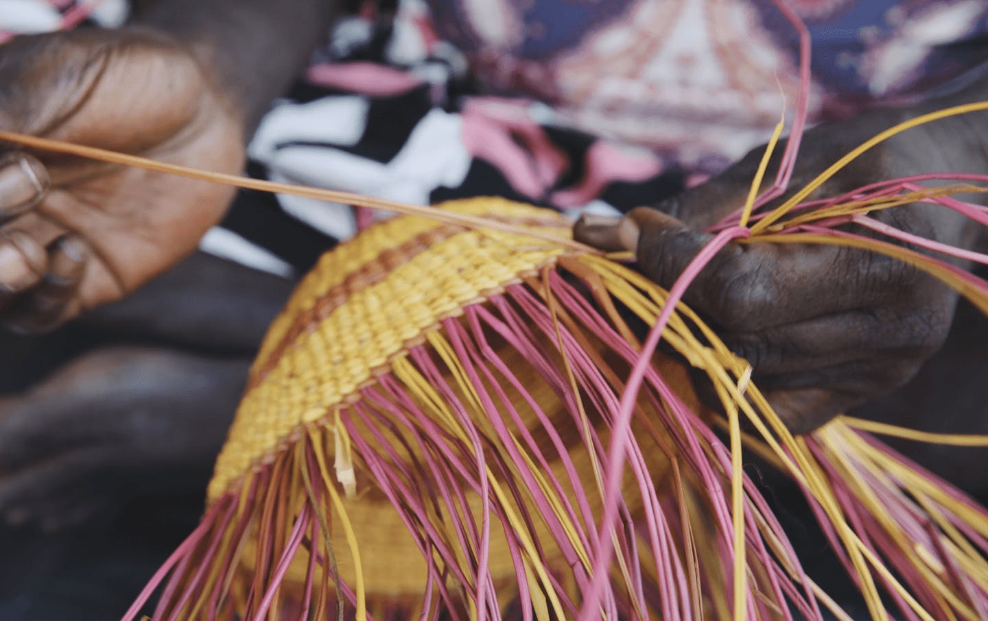 A person threading a woven piece of art.