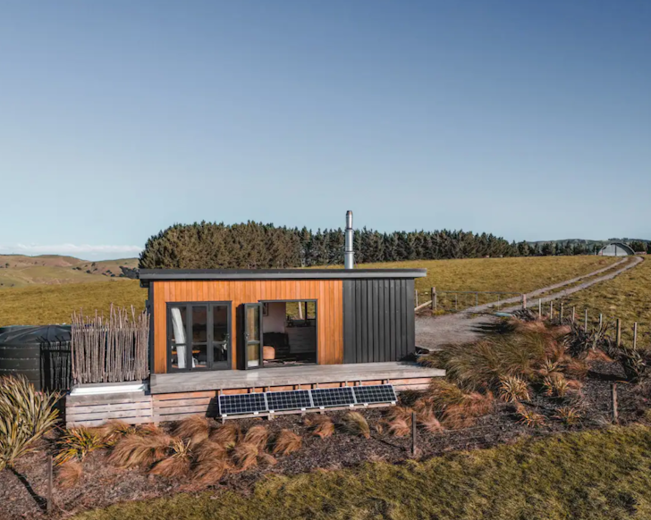 An exterior view of Tia Hut cabin surrounded by farm land in New Zealand