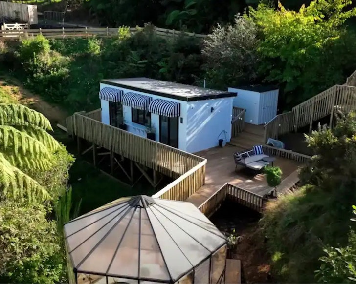 A view of the tiny house and greenhouse dining room at one of the best romantic stays in Wellington