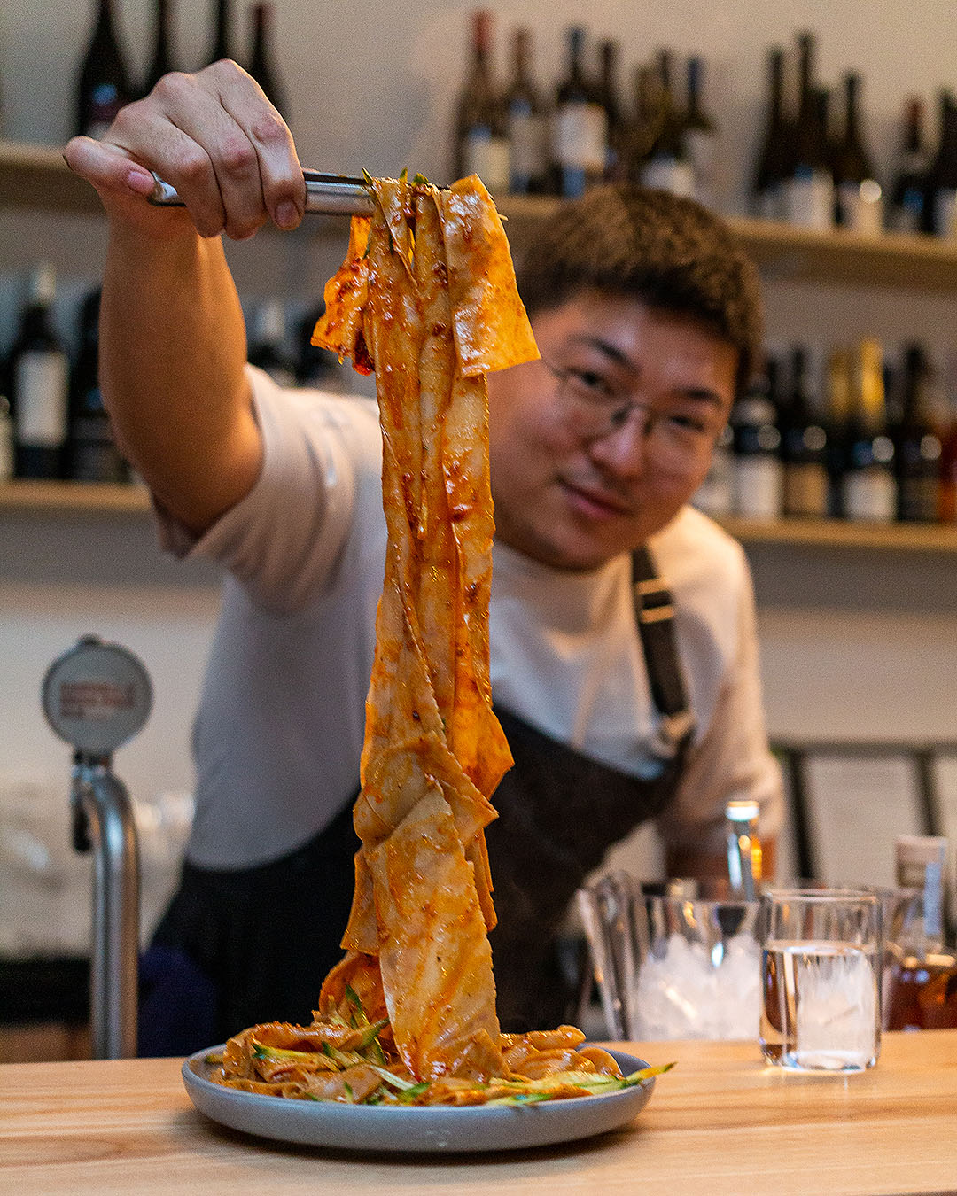 Jason Kim holds up the metre long noodles at Tokki, one of the best restaurants in Auckland.