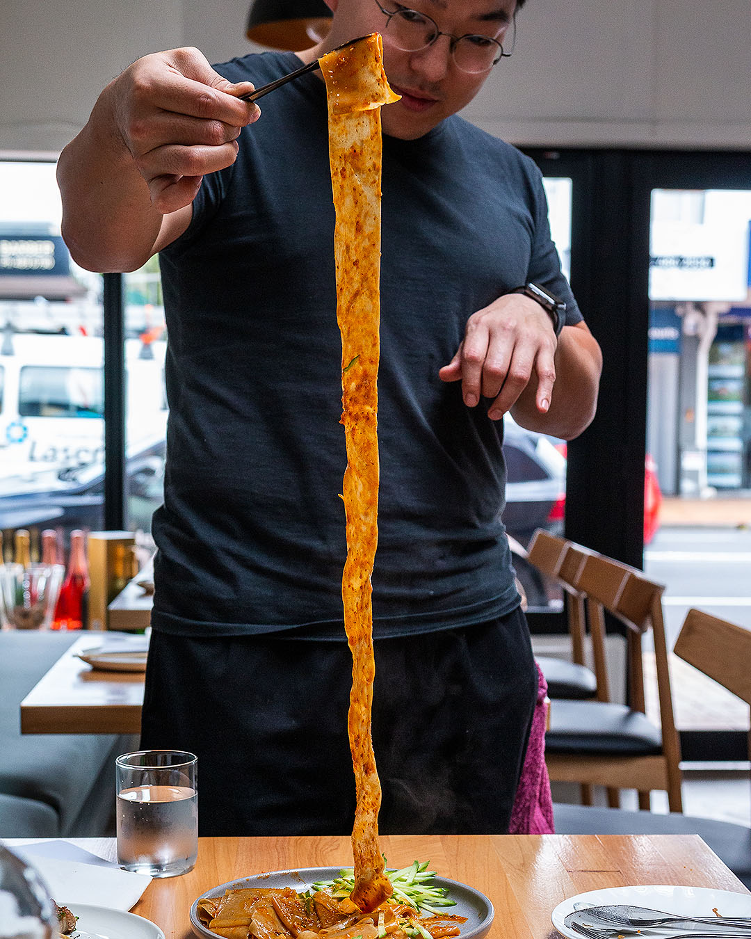 Jason Kim pulls up a metre-long noodle at Tokki, one of the best gluten-free eateries in auckland.