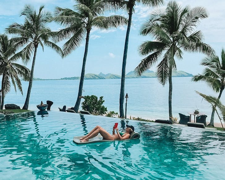 A woman floats on a lilo reading a book at Tokoriki Island Resort, Fiji. 