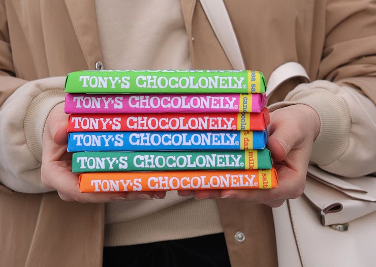 A girl holds 6 bars of Tony's chocolonely in her hands,