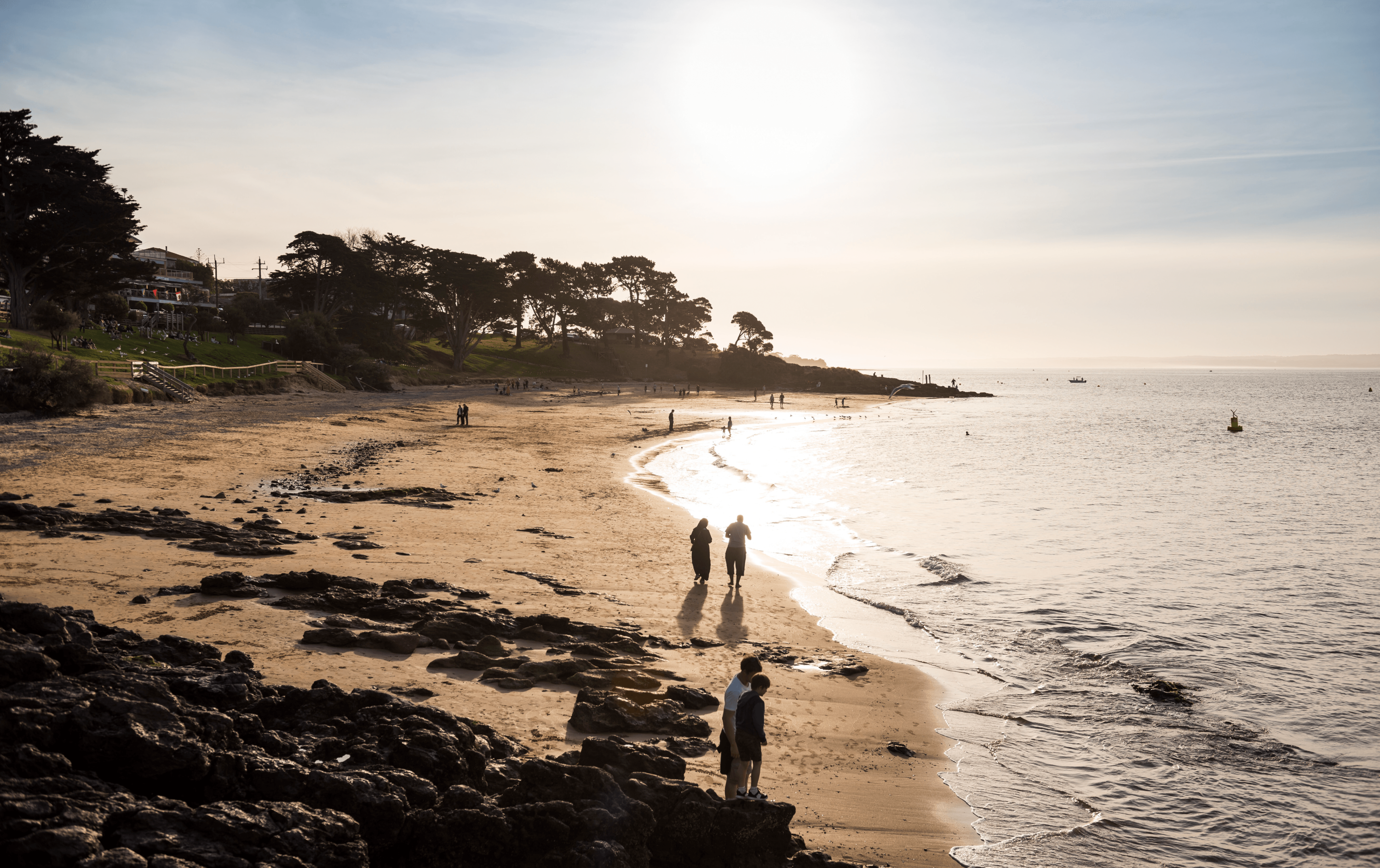 A group walking across the sand on a sunny day at one of the best beaches in Victoria.