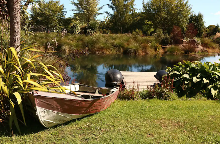 A wooden boat pulled up beside a jetty on the edge of a stream. 