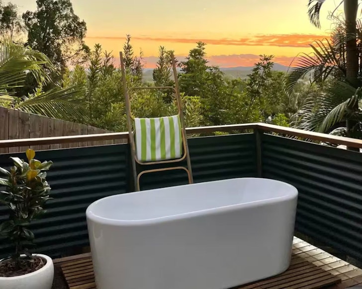 The outdoor bath with a sunset view at Treetop Beach House Airbnb Sunshine Coast