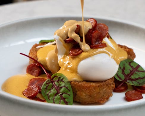 Pouring hollandaise onto eggs benedict.