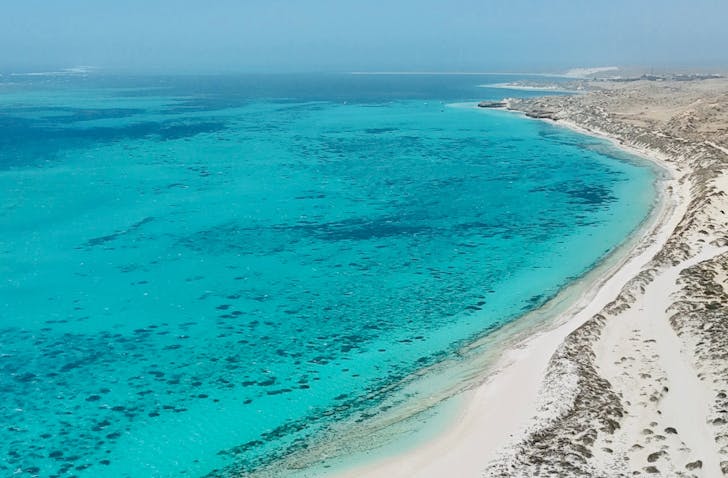 Turquoise sea, white beach, serene.