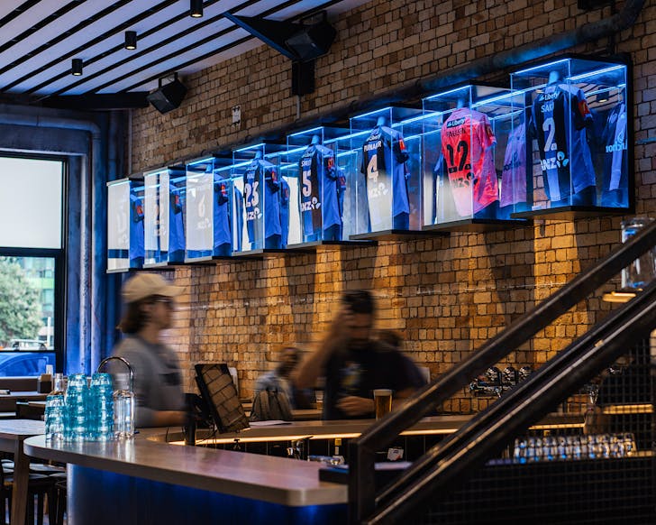 Auckland FC shirts on a brick wall at Tyler St Sport. 