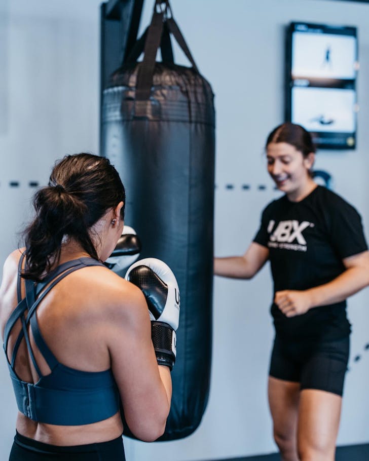 Two girls in the middle of boxing rounds on the bags at UBX in Townsville.