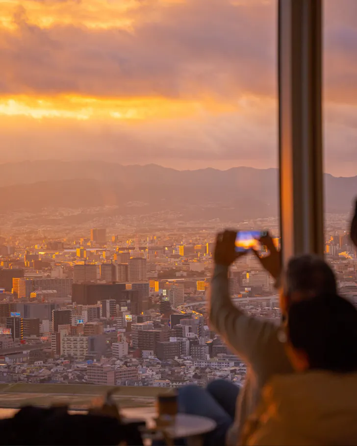A traveller taking a photo of the beautiful sunset at the top of Umeda Sky Building in Osaka.