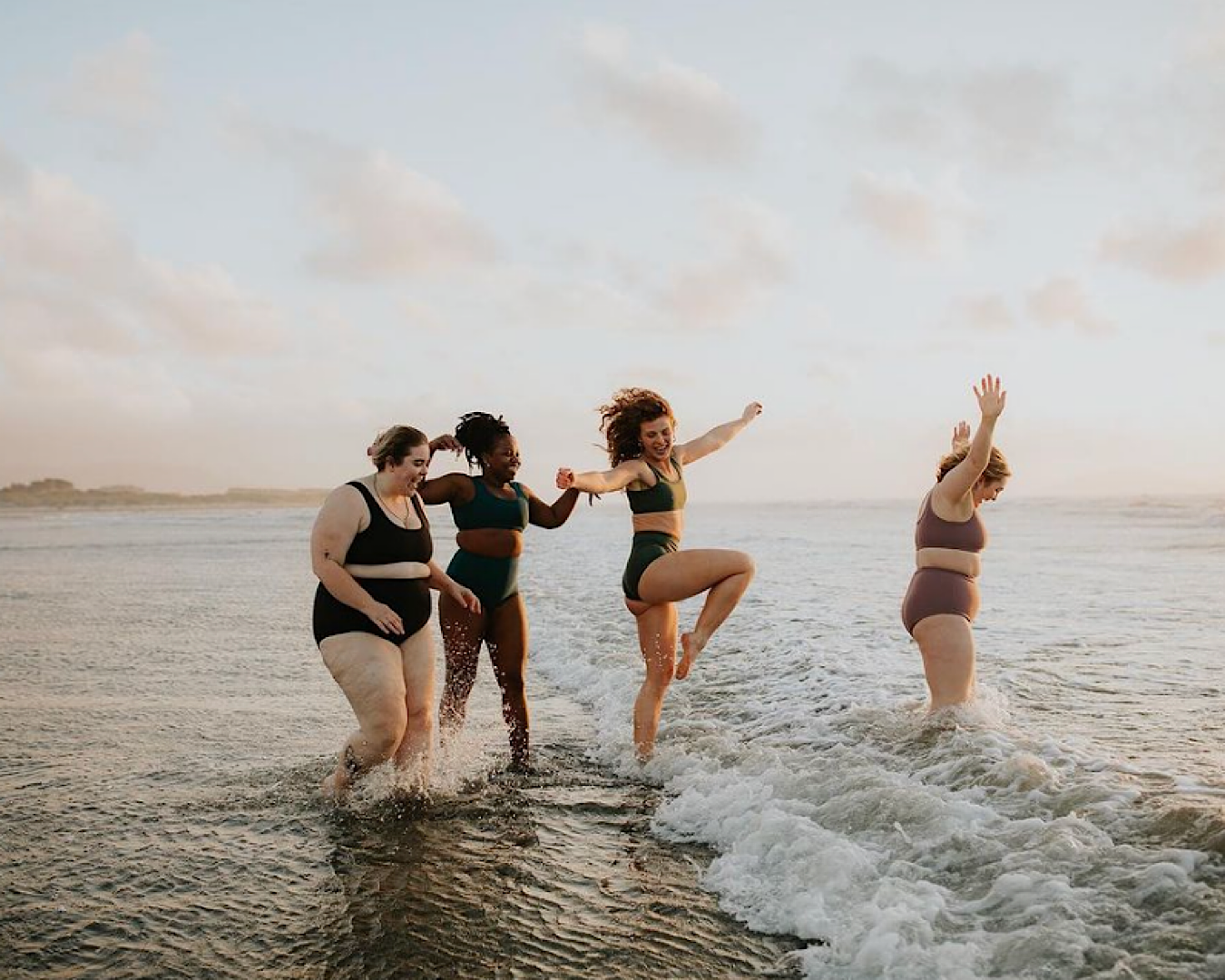 Four women live their best life in the shallows at a beach, all wearing Unde, one of the coolest swimwear labels in NZ. 