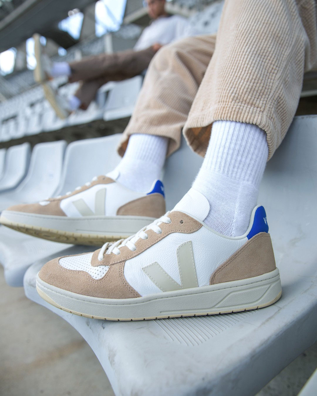 Beige and white Veja sneakers worn with long white socks and beige corduroy pants.
