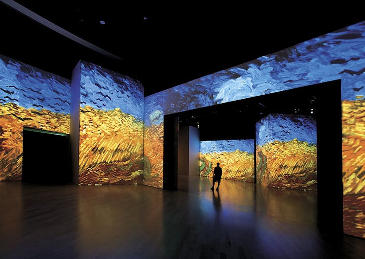 A person walks amongst a massive Van Gogh painting.