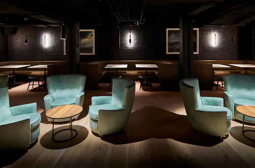 The dimly lit interior of Valhalla with suede cyan blue chairs and booth seating in the background 
