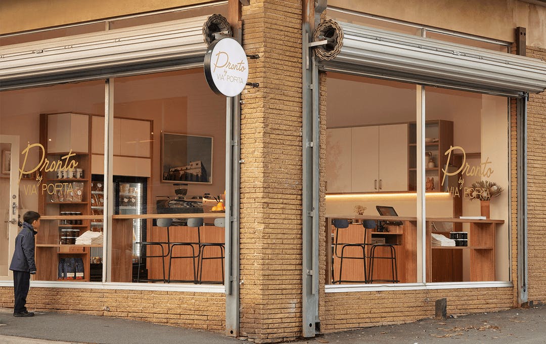 The outside of a cafe with a child looking through the window. 