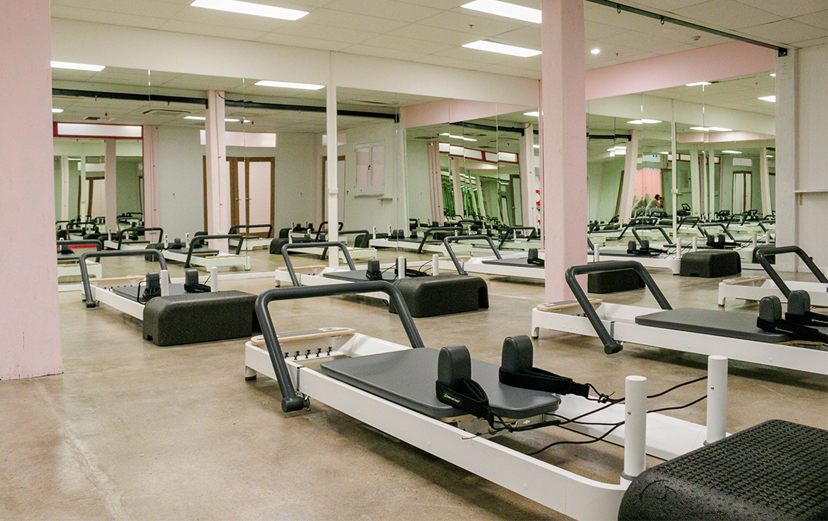 A mirror lined room filled with reformer beds.