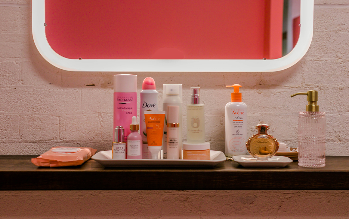 Beauty products arranged on a bench in front of a mirror