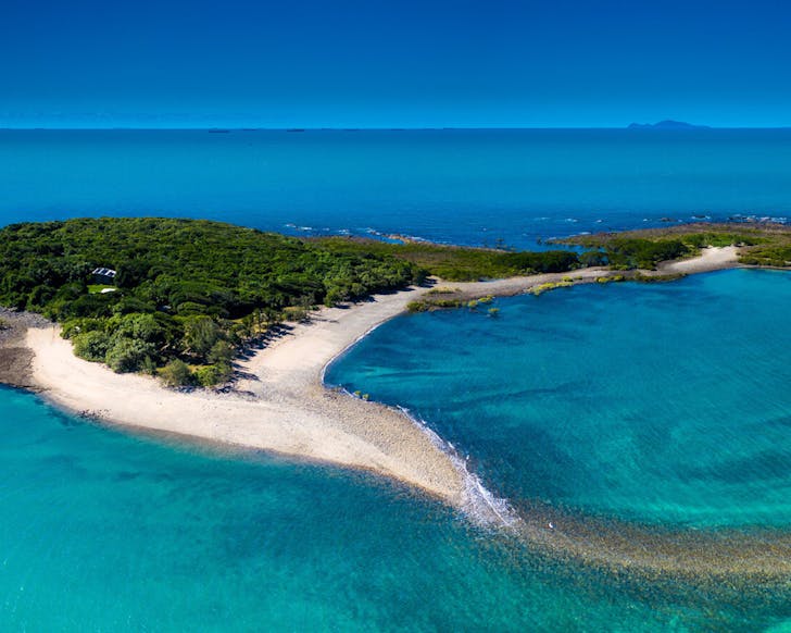 Victor Island in the Whitsundays. A small lush island surrounded by clear blue water.