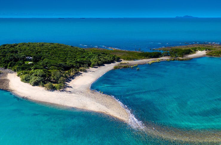 A small sandy island surrounded by clear blue waters