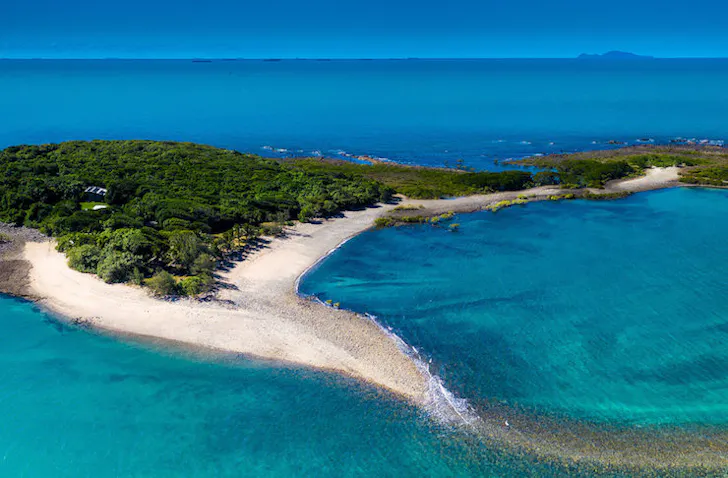 A small sandy island surrounded by clear blue waters
