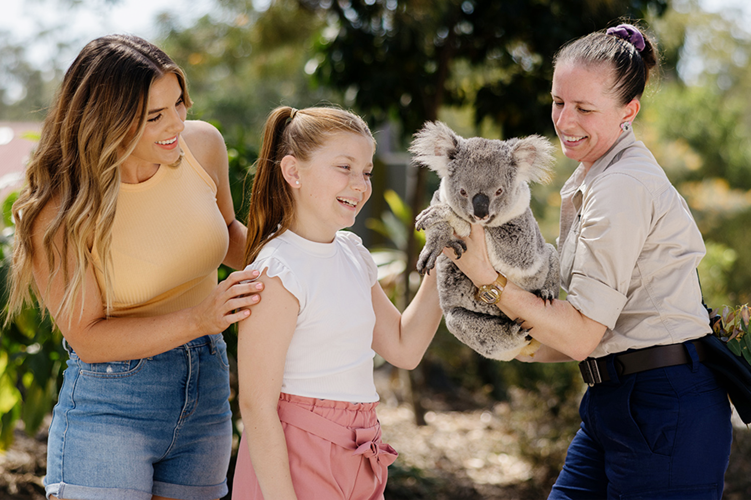 Woman, child, koala and park attendee. 