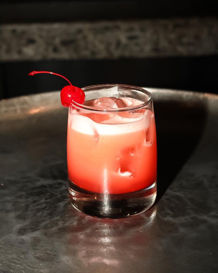 A gorgeous pink-hued cocktail topped with a cherry from Vine Eatery & Bar. 