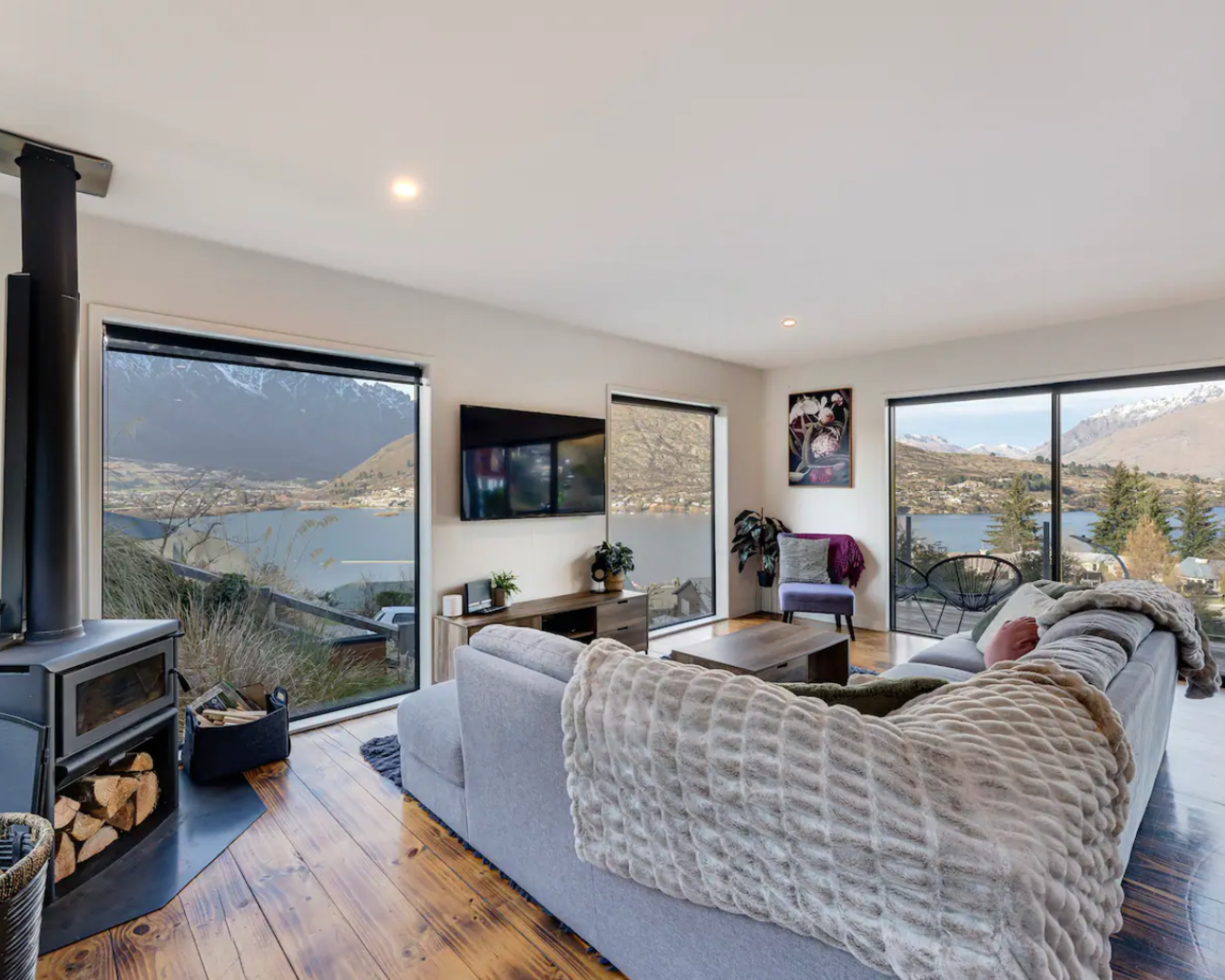 Living room with large sofa, wood fire and panoramic views of Queenstown