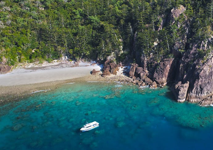 A boat is anchored in secluded cove. 