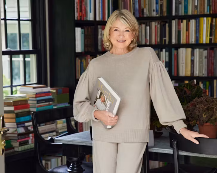 martha stewart stands in her home holding a book