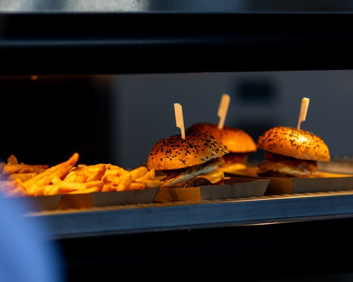 three burgers with chips under warm light