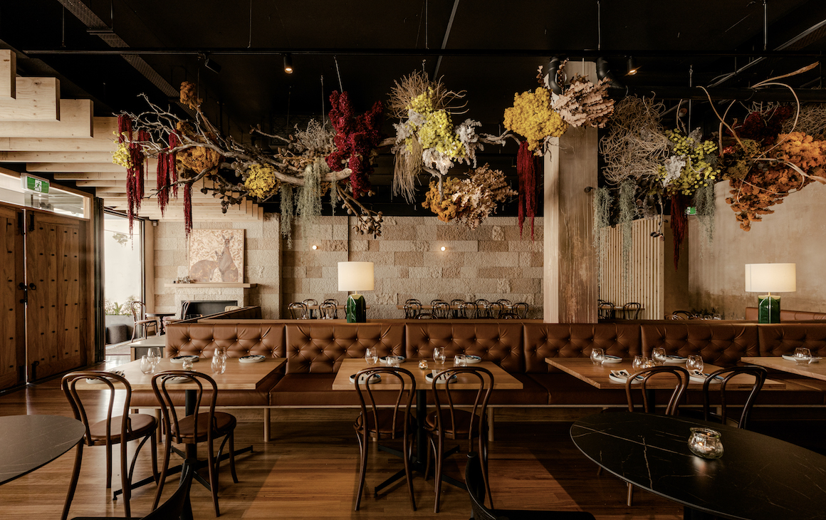 a row of dining tables with native flowers hanging above