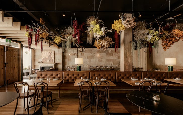 a row of dining tables with native flowers hanging above