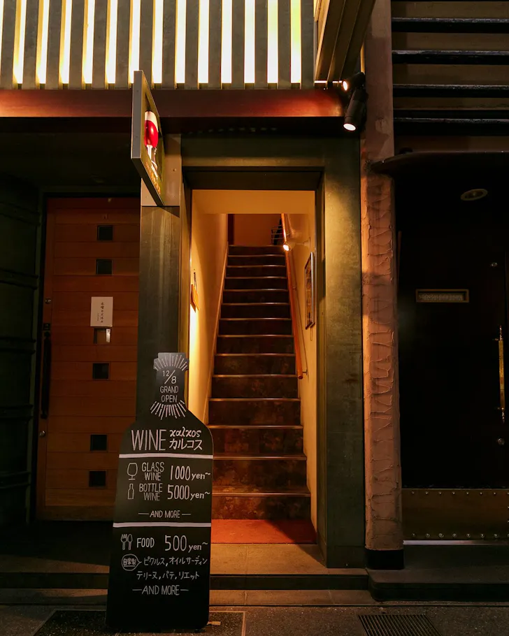 A narrow staircase leading up to Wine Bar Calcos in Osaka.