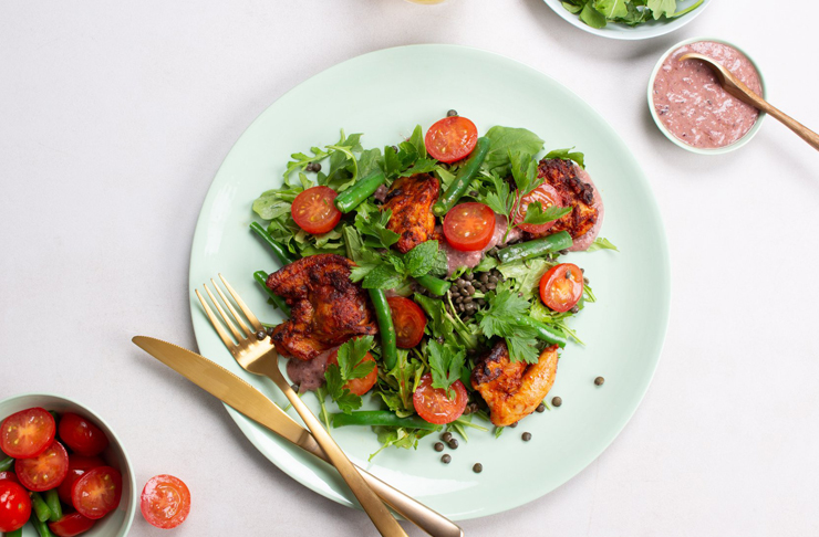A chicken salad with a variety of greens, mint and cherry tomatoes