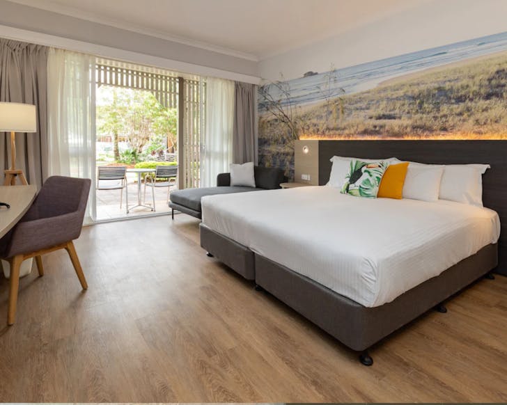 Large bed in front of beach wallpaper