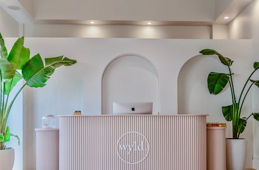 A beautiful, minimalist pink and white reception area studded with green plants. 