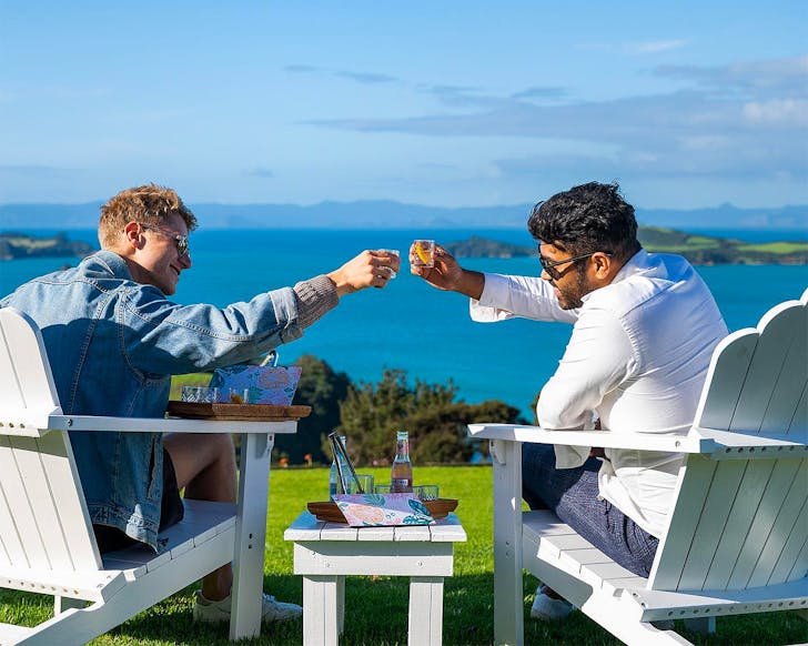 Two dudes cheers overlooking an incredible ocean view at Waiheke Distilling Co