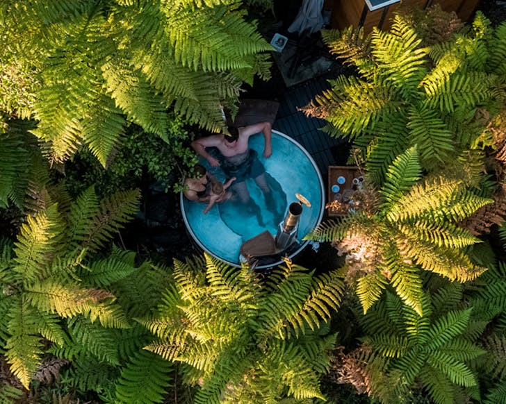 People enjoying the Waiho Hot Tubs, surrounded by native bush. 