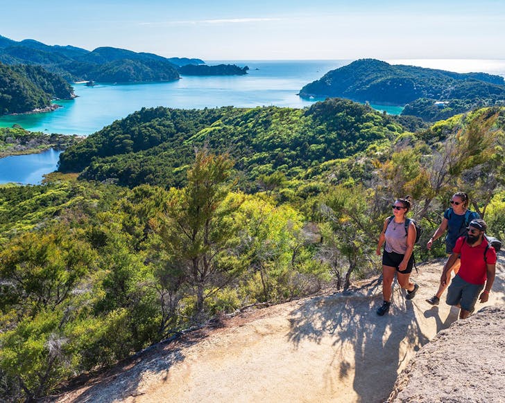 Three people are seen walking Anchorage Abel Tasman.