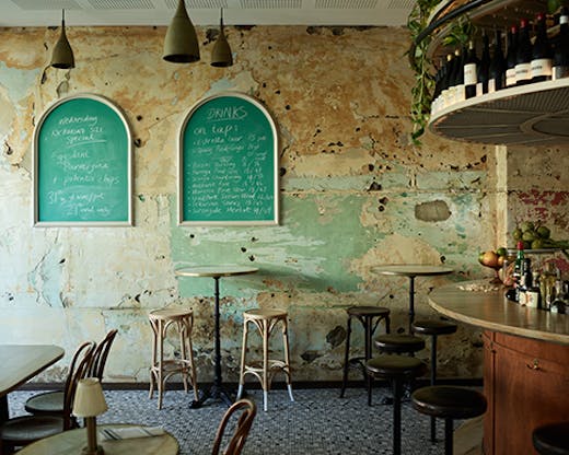 The inside of the bar with paint stripped walls, bar stools, and wine.