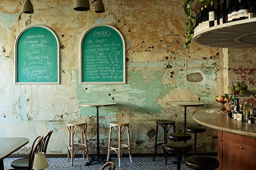 The inside of the bar with paint stripped walls, bar stools, and wine.